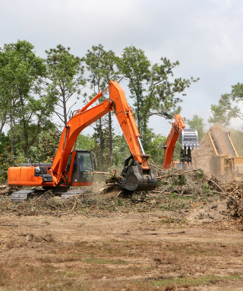 An orange excavator digging through a field